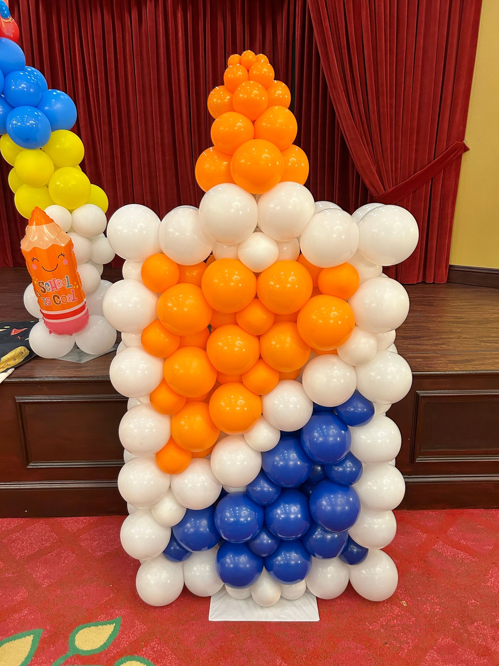 A wall covered in black , gold and white balloons for a birthday party.