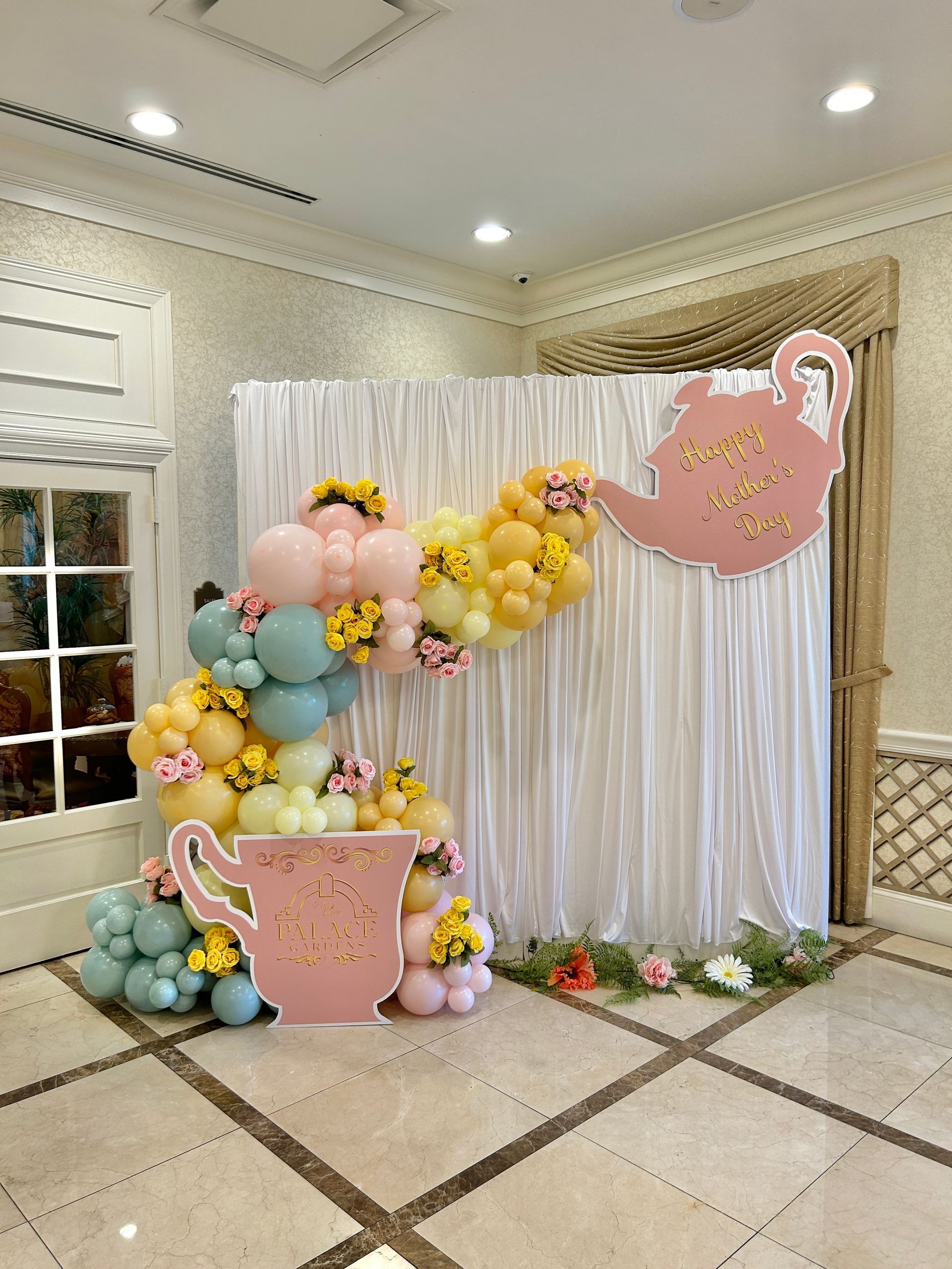 A wall covered in black , gold and white balloons for a birthday party.