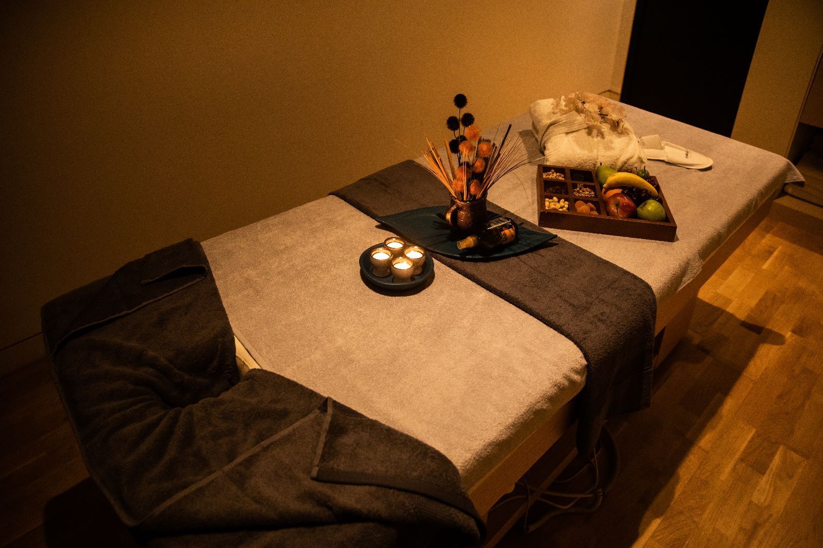 Two massage beds with candles and fruit on them in a room.