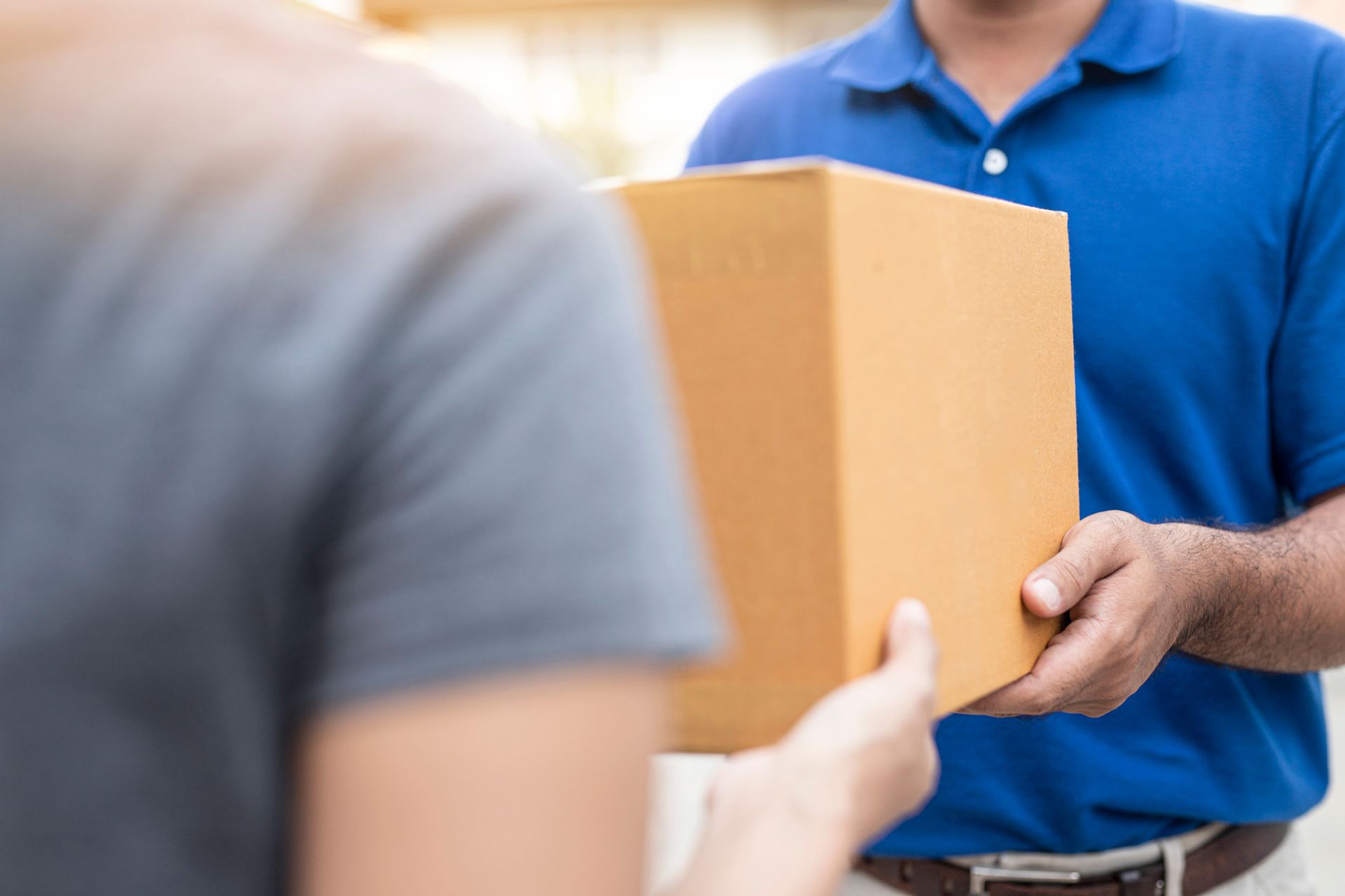 A delivery man is handing a box to a woman.
