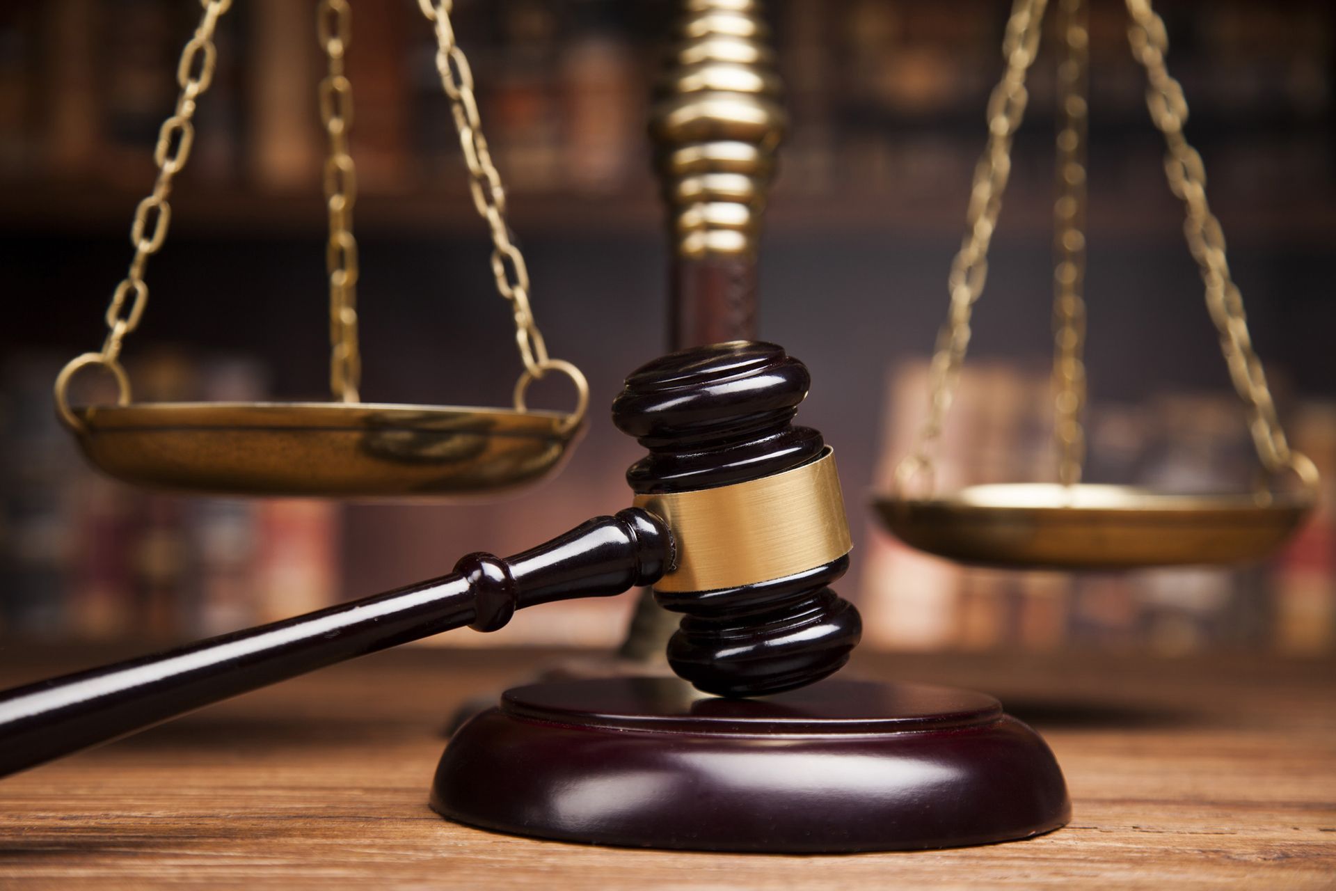 A judge's gavel and scales of justice on a wooden table.