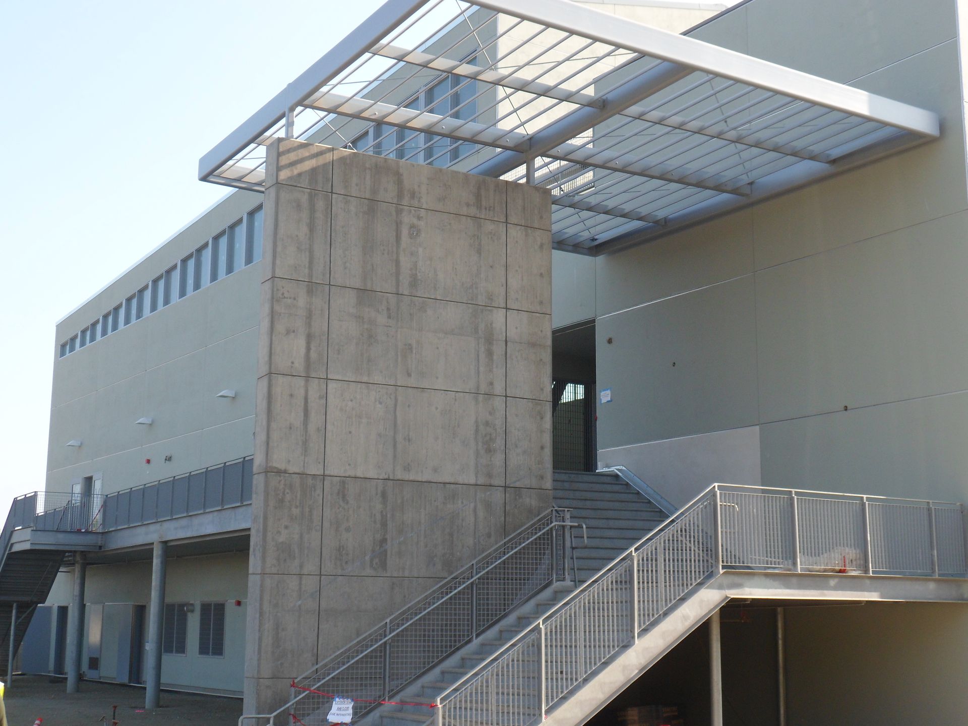 Exterior of a modern building with concrete pillar, stairs, and metal awning.