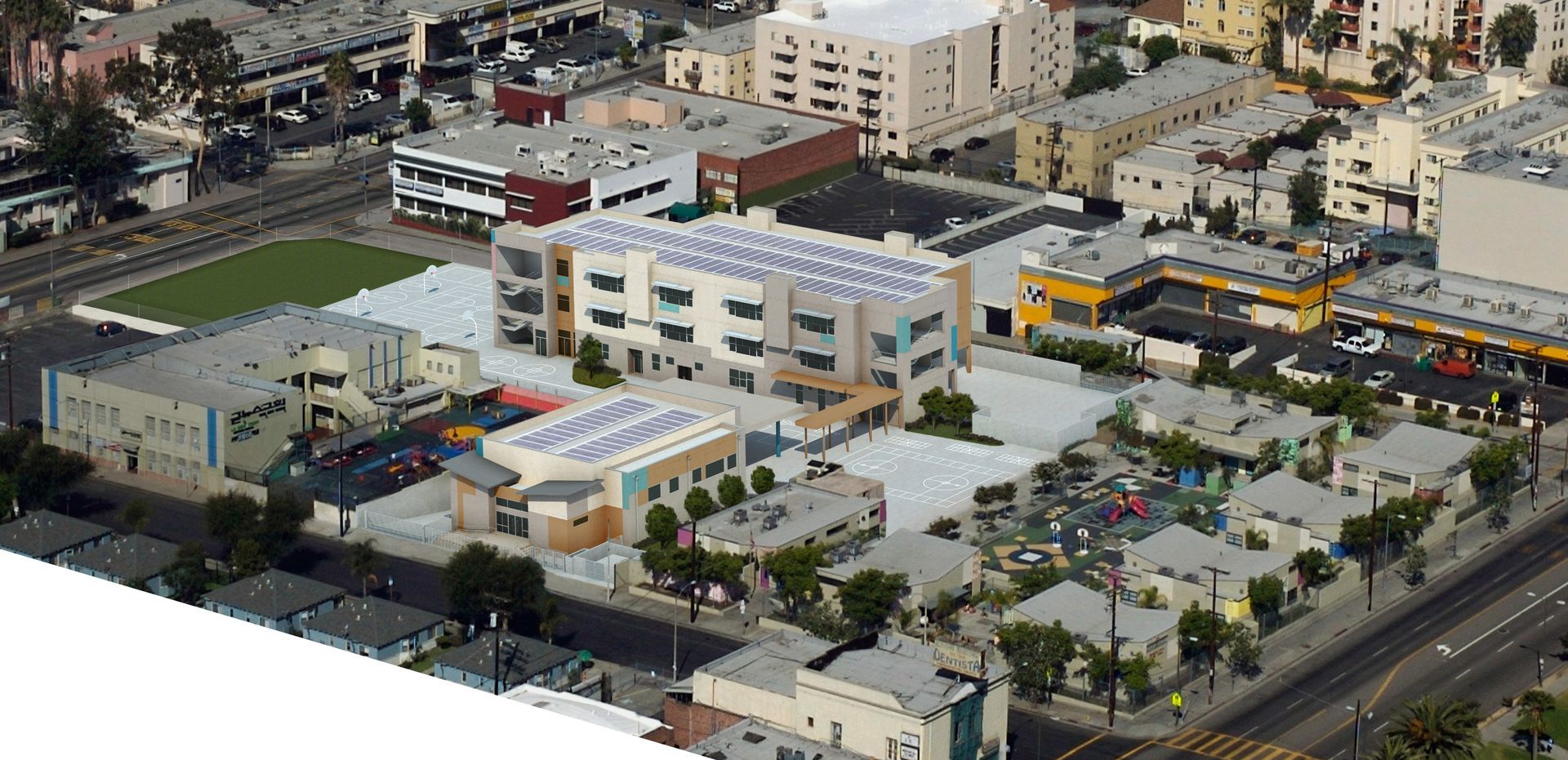 Aerial view of a complex with buildings, a green field, and streets, possibly a school or community center in an urban area.