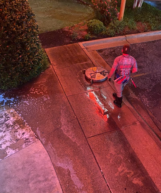 A man is cleaning a building with a high pressure washer.