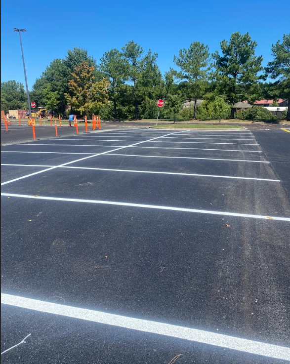 An empty parking garage with pink columns and yellow arrows.