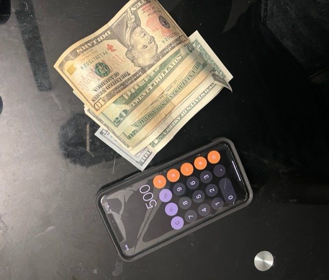 Money and phone calculator on glass table.