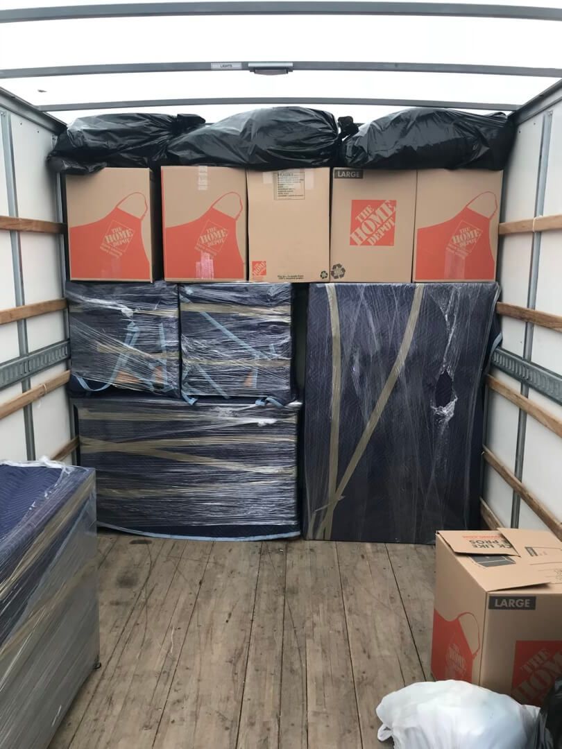 Loading up a 26' truck with padded furniture on the bottom with boxes and bags stacked on top.