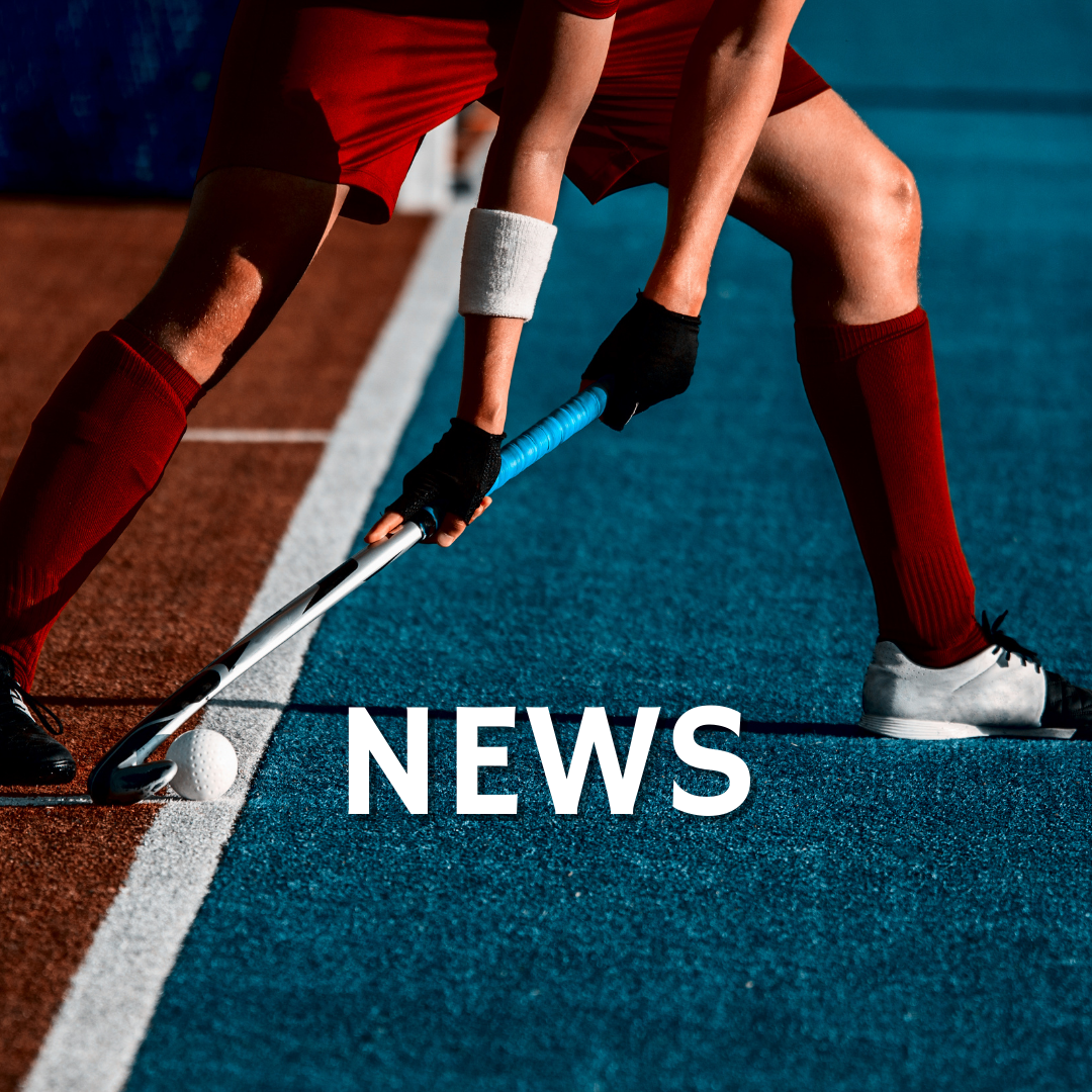 A person is playing field hockey on a blue field