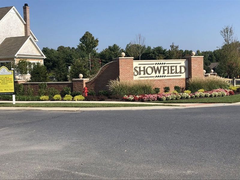 Showfield neighborhood entrance sign, brick structure with landscaping, under a clear sky.
