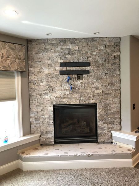 Fireplace with gray stacked stone, black firebox, and a raised hearth.