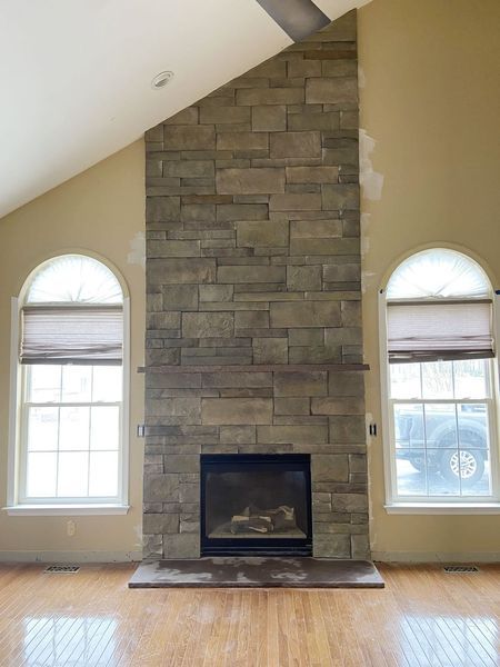 Stone fireplace with a dark insert, flanked by arched windows.