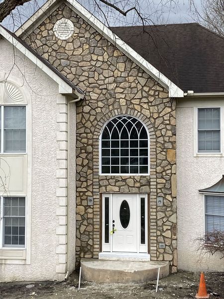 House exterior with stone facade around arched window and door; stucco siding.