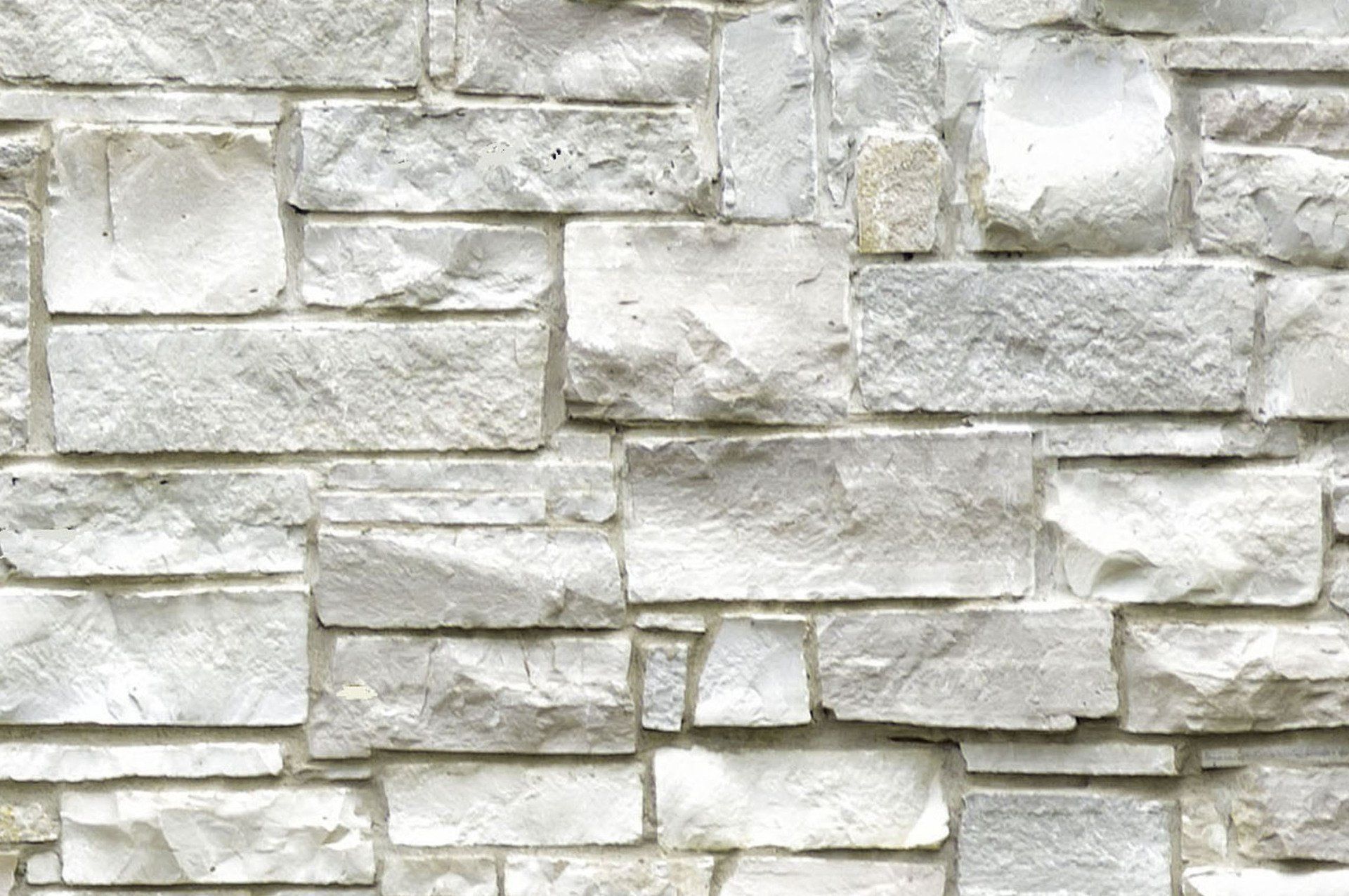 White stone wall with varied rectangular and square blocks.