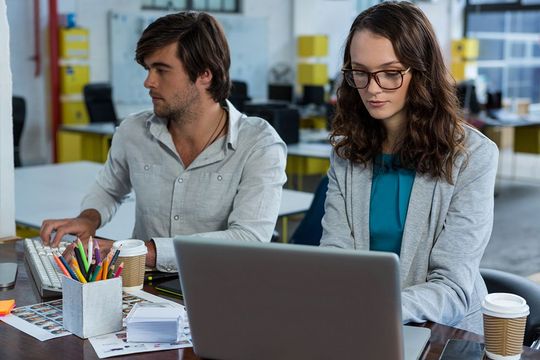 a man and a woman sitting at a table with a laptop