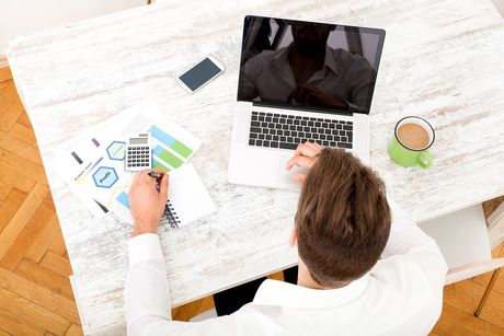 a man sitting at a table working on a laptop