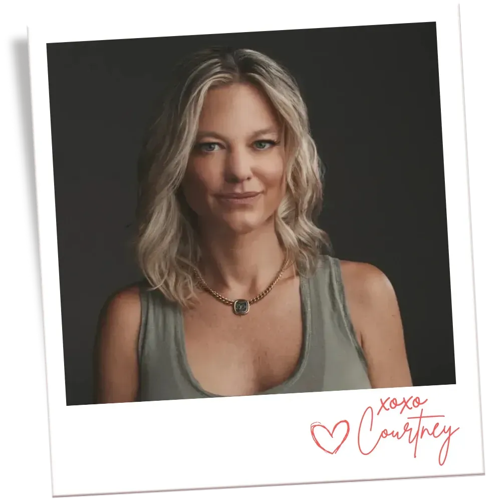 Blonde woman kissing a Bernese Mountain Dog on the head indoors. Dog is black, white, and brown.