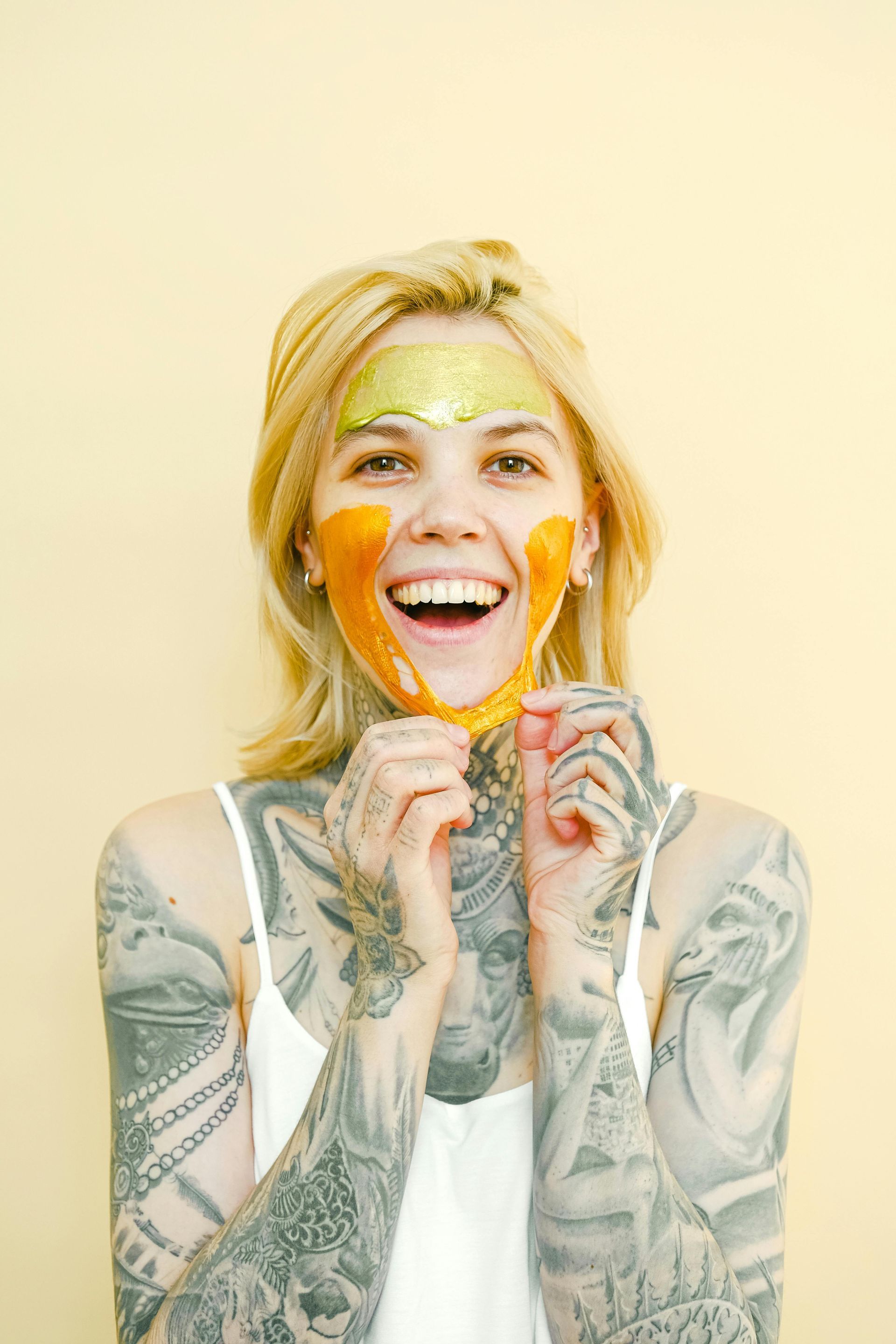 A woman with tattoos on her arms is holding a mask on her face.