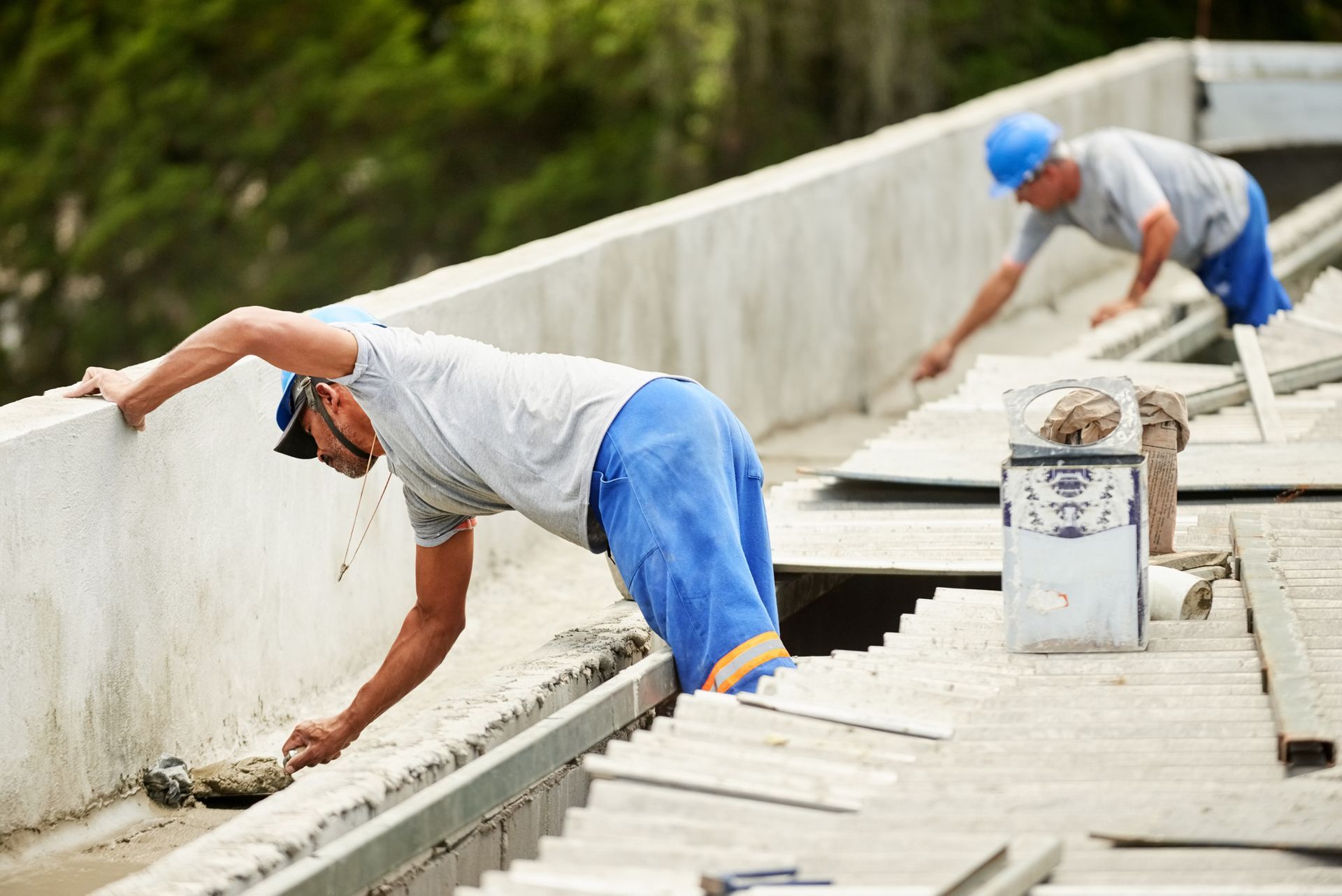 Two contractors wearing blue pants are performing commercial roofing services, finishing roof work.