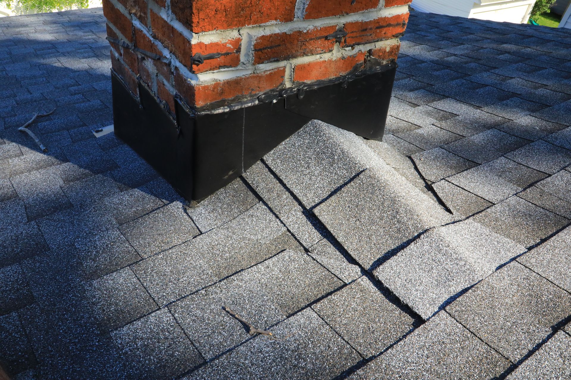 Brick chimney with black flashing on a gray shingle roof.