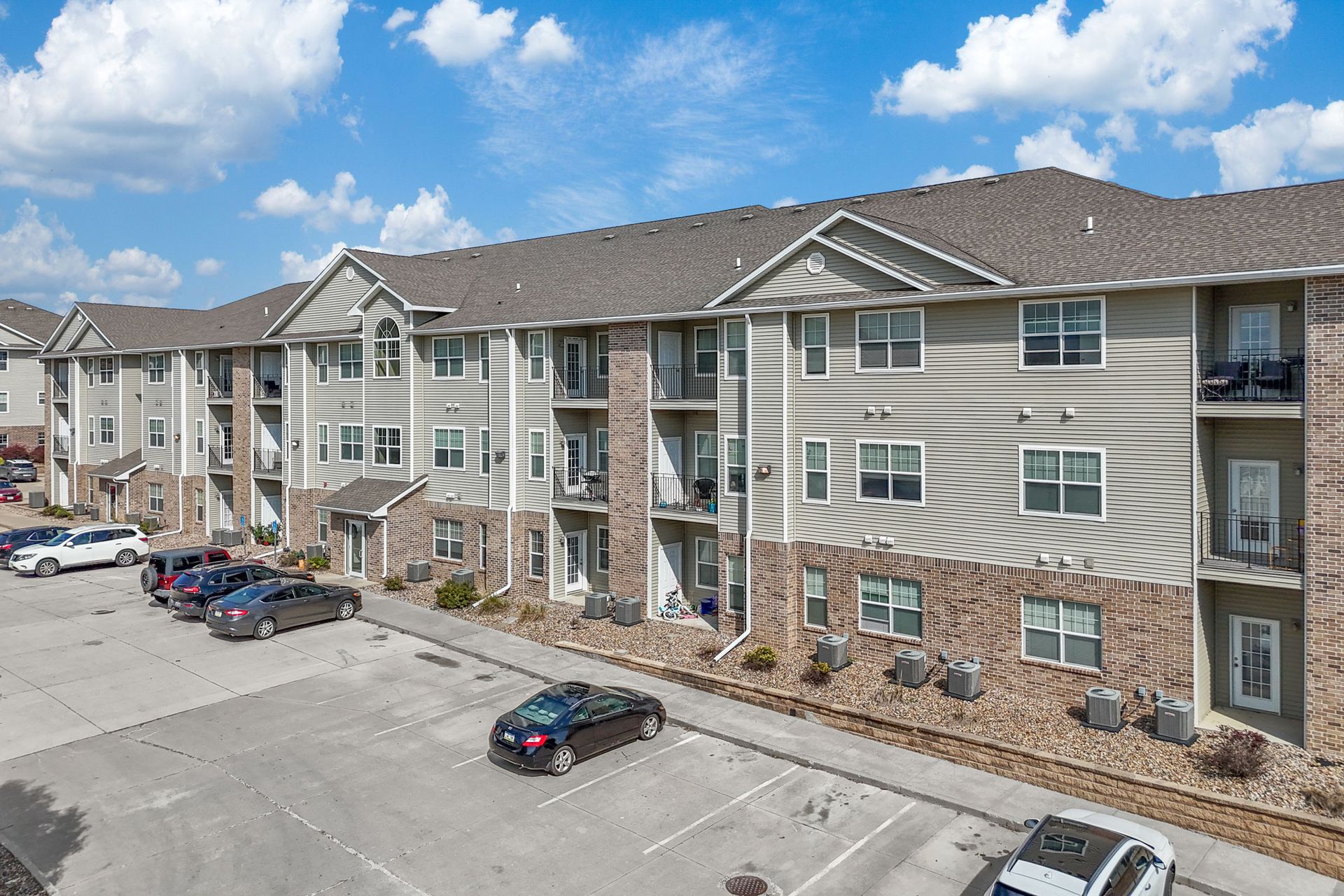 Aerial view of apartment complex in a rural setting under a cloudy sky.