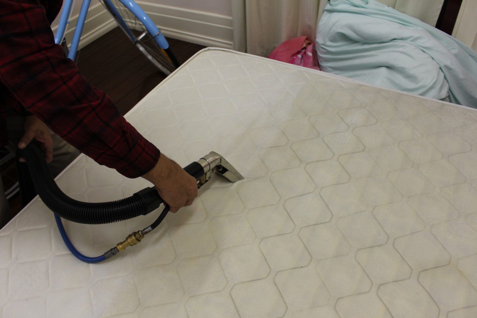 A person using a vacuum cleaner to clean a mattress, effectively removing dust, dirt, and allergens.
