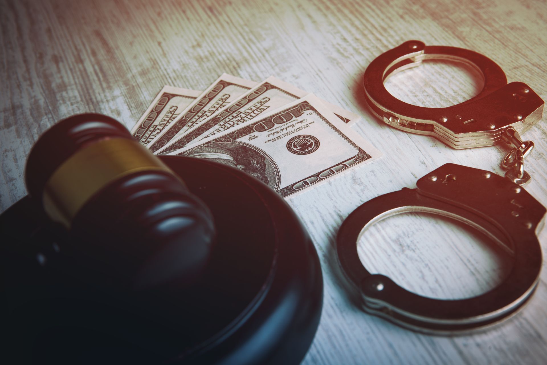 Gavel, money, and handcuffs on a wooden surface, symbolizing crime and justice.