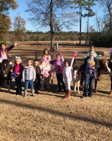 A group of children standing next to horses in a field.