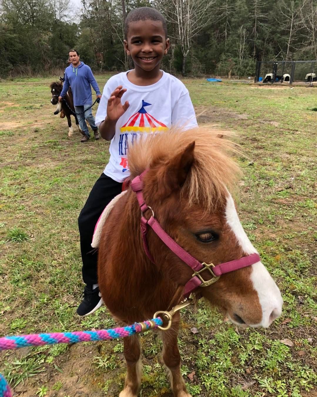 A young boy is riding a brown and white pony in a field.