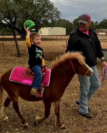 A little girl is riding on the back of a brown pony