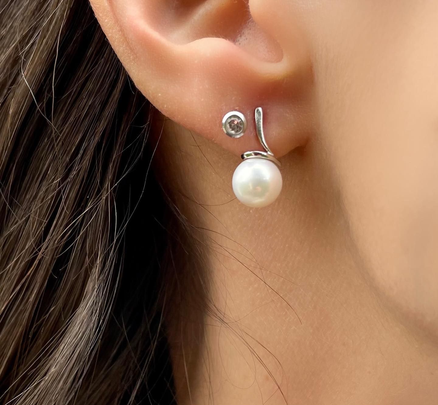 Un primo piano dell'orecchio di una donna con un paio di orecchini di perle
