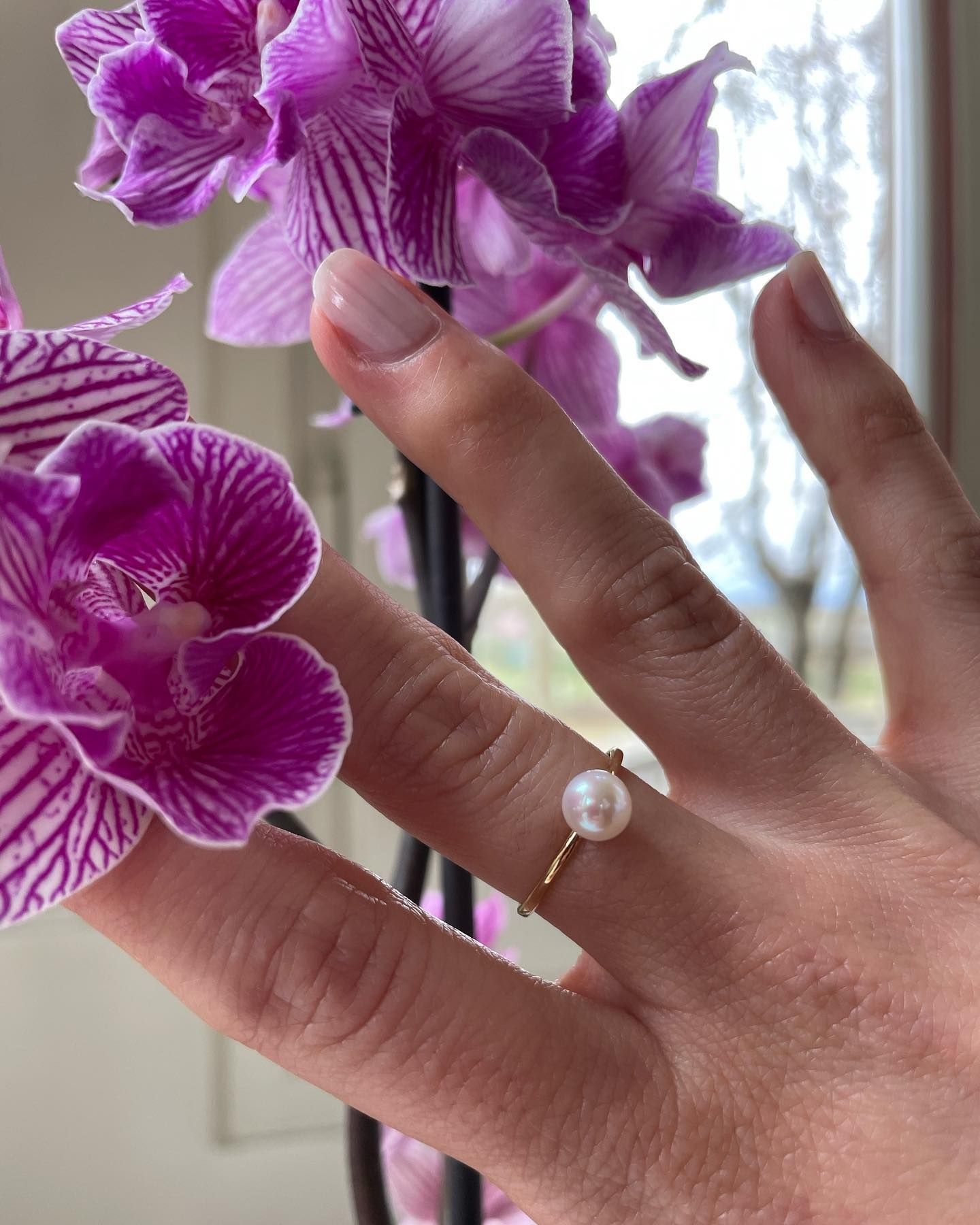 Primo piano della mano di una persona con un anello che tiene dei fiori viola.