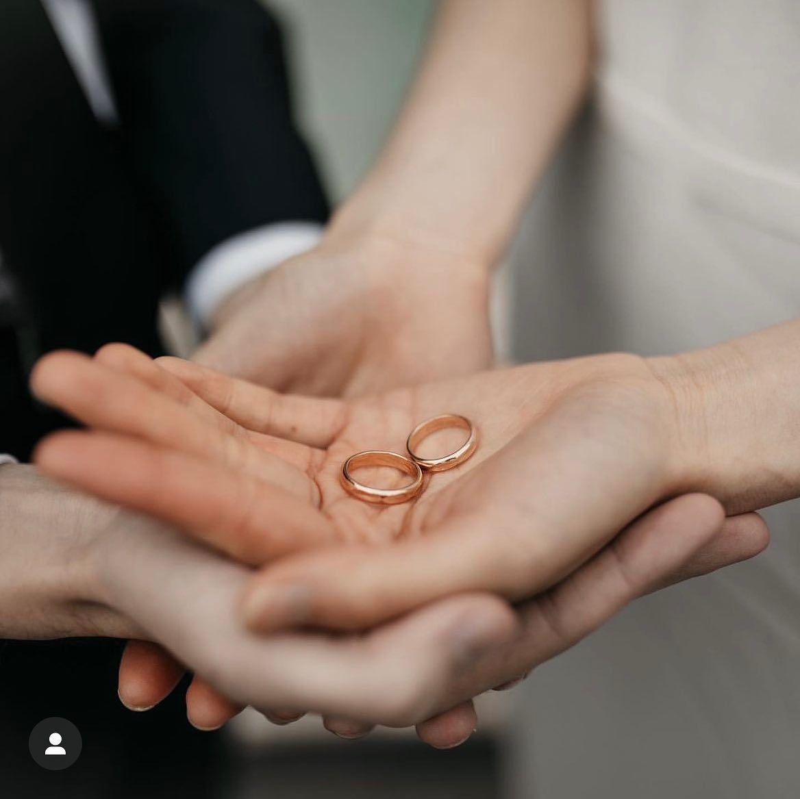 Una sposa e uno sposo tengono le fedi nuziali tra le mani