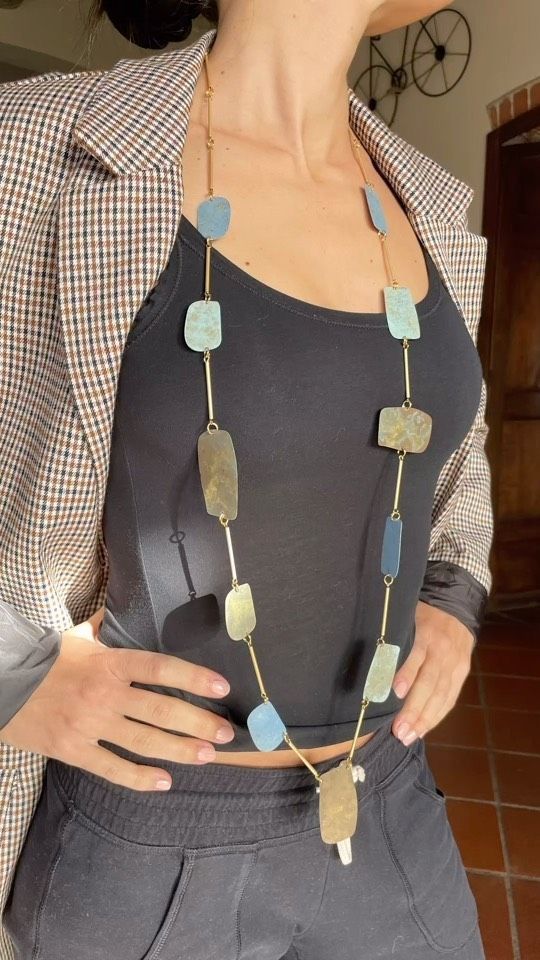 Una donna indossa una lunga collana e una giacca scozzese.