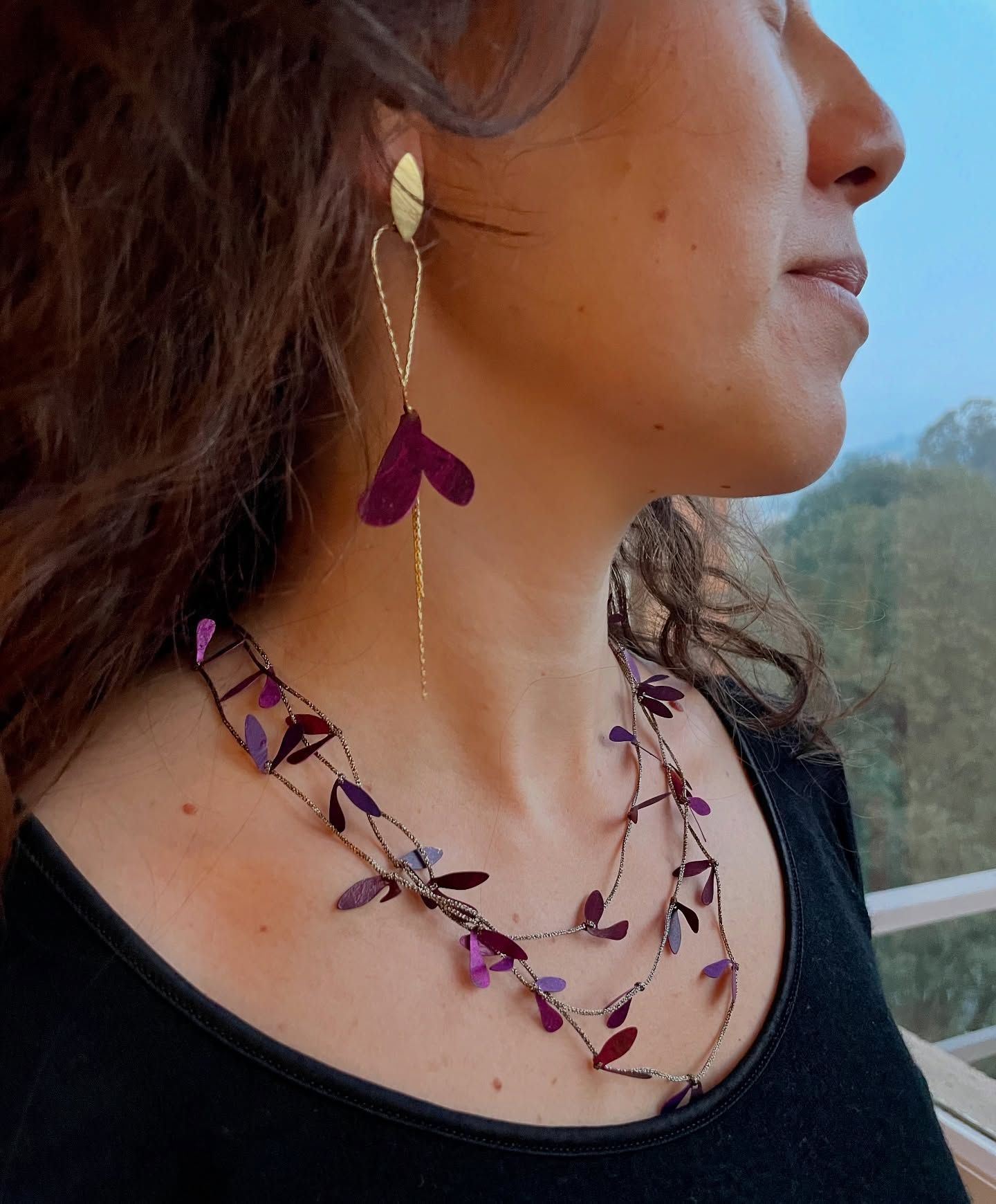 Una donna che indossa una collana e orecchini con foglie viola