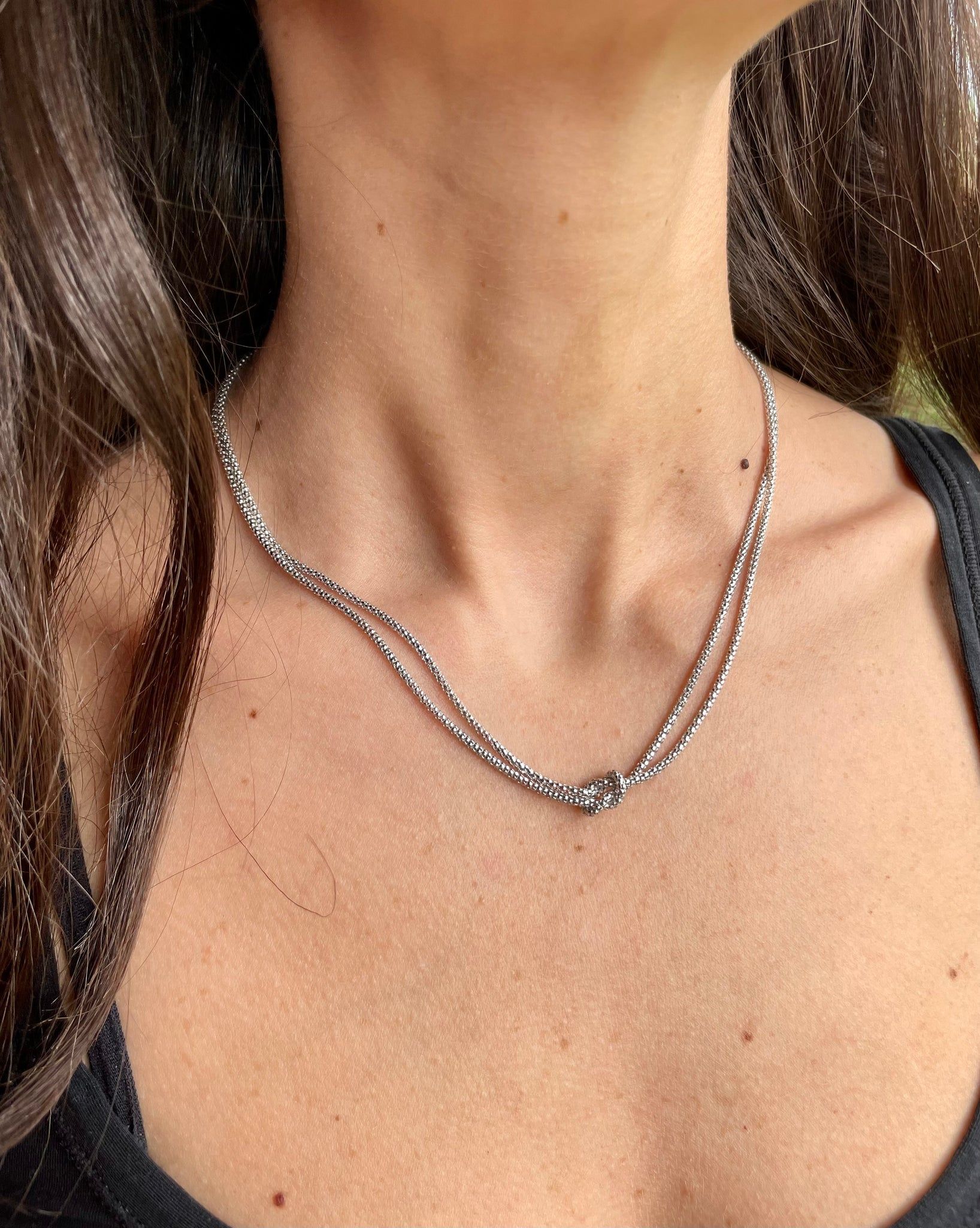 Una donna indossa una collana d'argento intorno al collo.