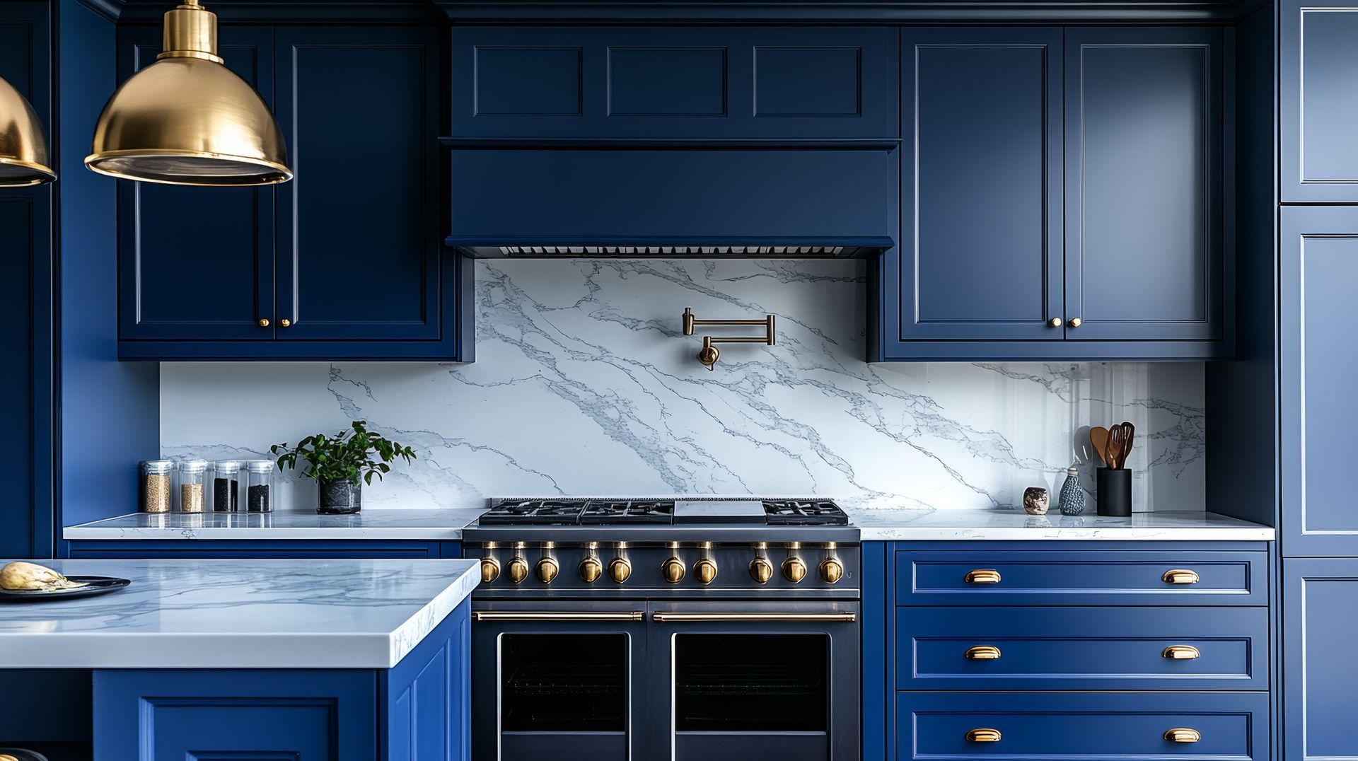 Navy blue kitchen with gold accents and marble backsplash.