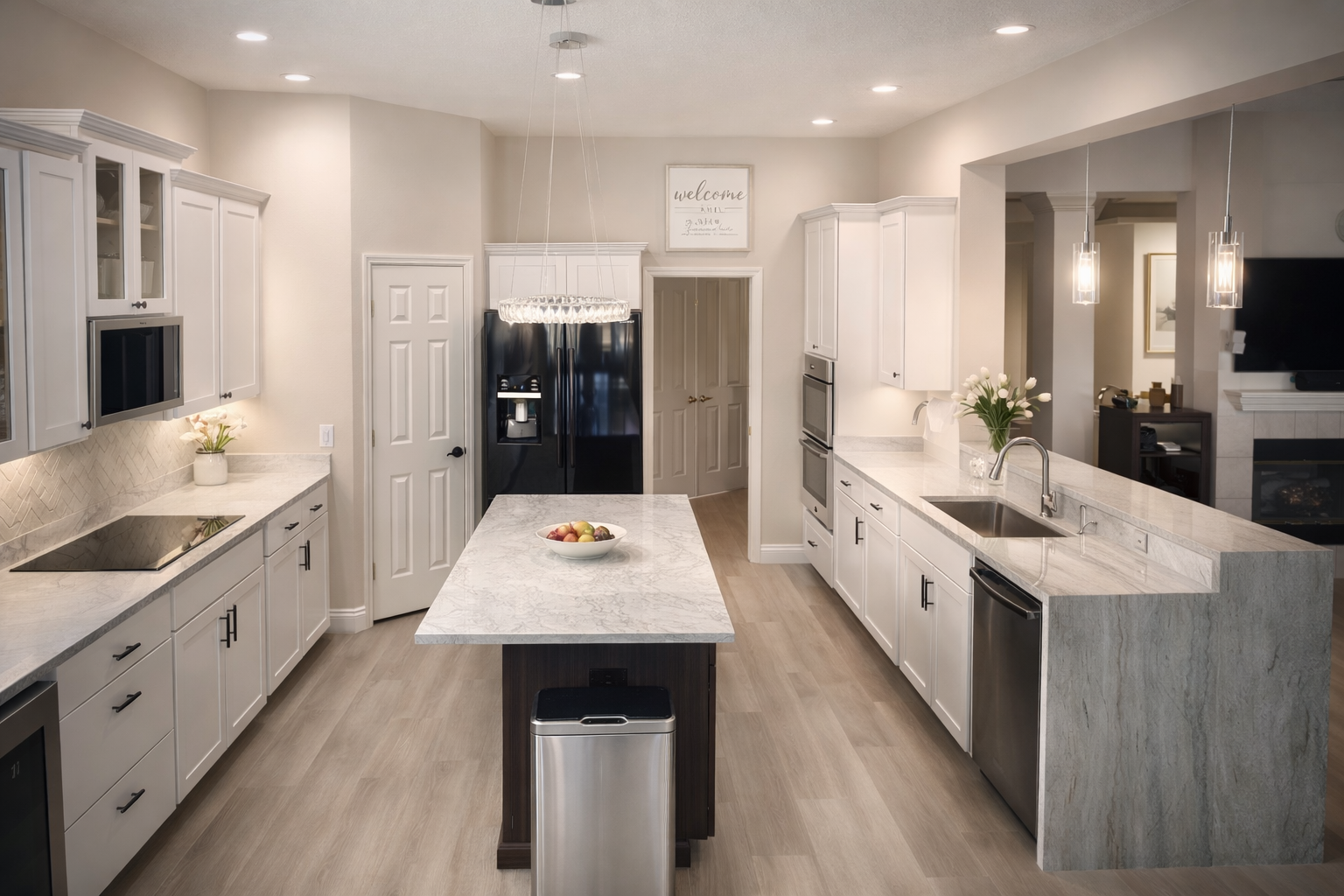 Spacious modern kitchen with white cabinetry, light countertops, and an island with a stainless steel trash can.