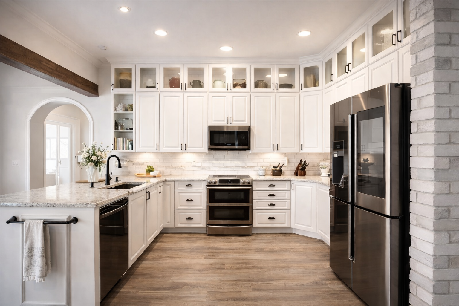 White kitchen with upper glass-front cabinets, stainless steel appliances, and wood flooring.
