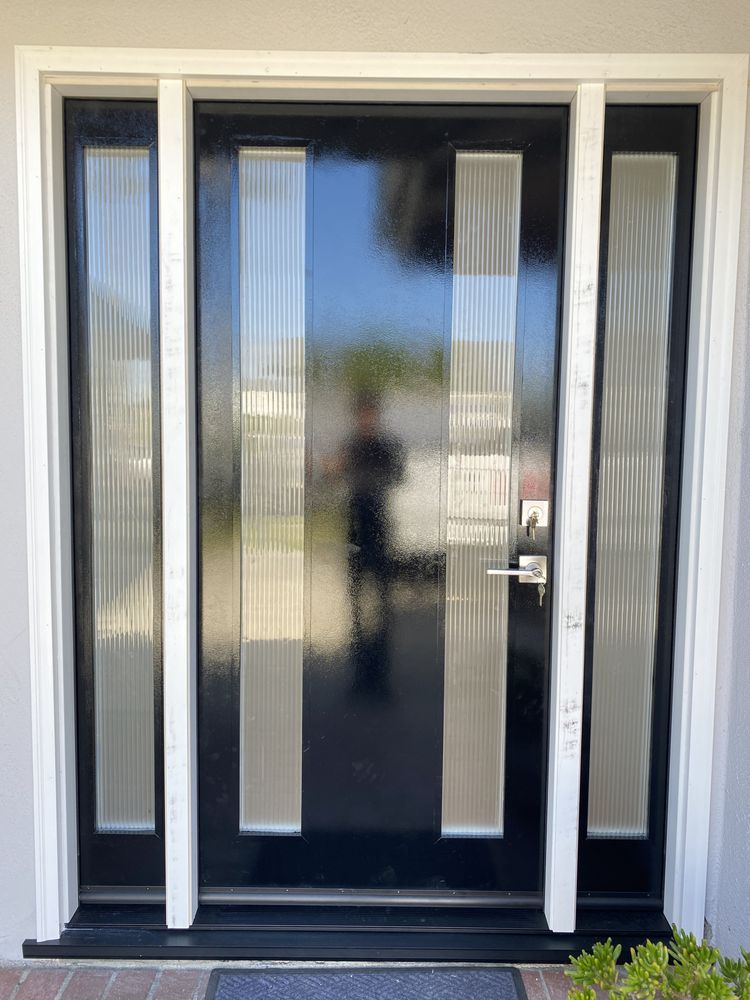 Black front door with narrow frosted glass side panels and white trim at a house entrance