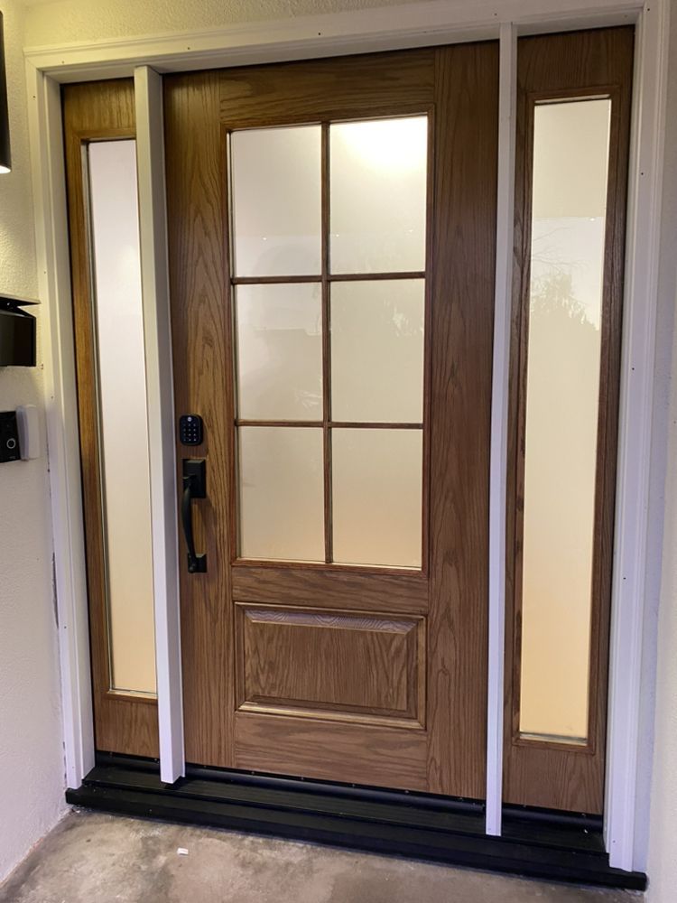 Wooden front door with frosted glass panels and white trim, viewed from inside a home.