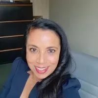 Woman with dark hair smiling, wearing a blue blazer, in front of a black cabinet.