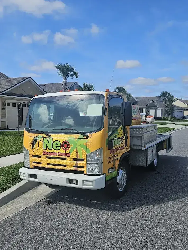 A yellow truck is parked on the side of the road in front of a house for pest Control