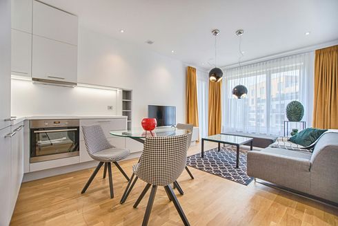 A living room with a dining table and chairs , a couch , and a television.