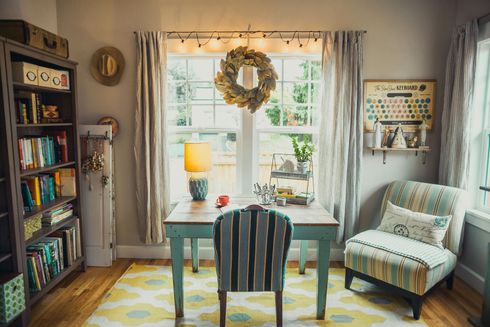 A home office with a desk , chair , lamp and bookshelf.