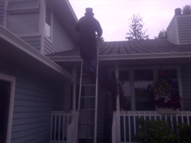 Man Climbing The Ladder To Get On House Roof
