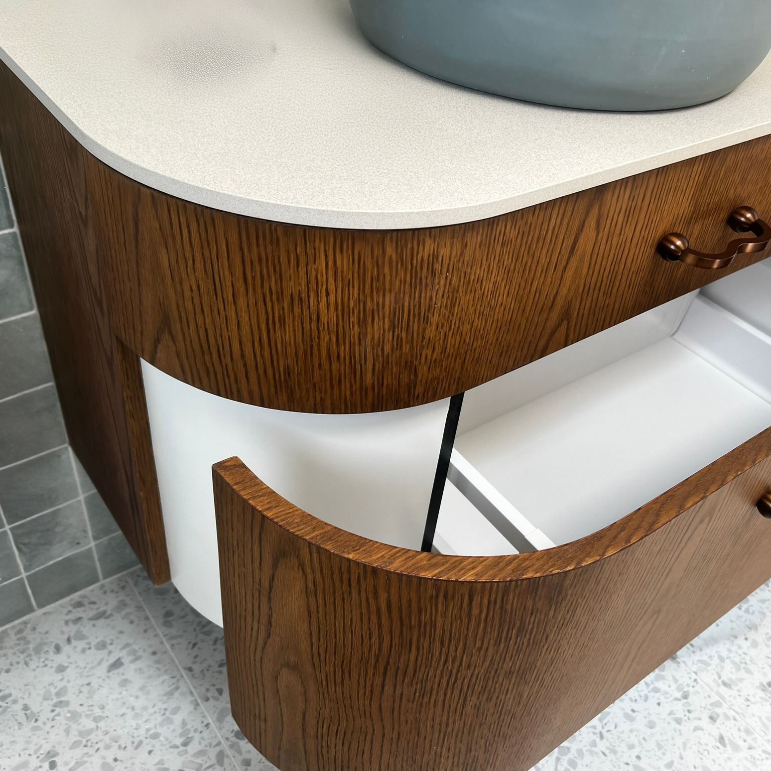 Wooden bathroom vanity with curved drawer open, white countertop, and grey sink.— Onyx Detailed Joinery in Unanderra, NSW