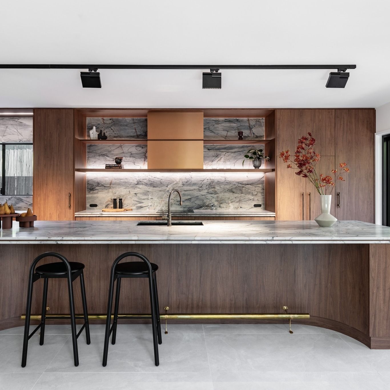 Modern kitchen with wood cabinetry, marble countertops, and black bar stools. — Onyx Detailed Joinery in Unanderra, NSW