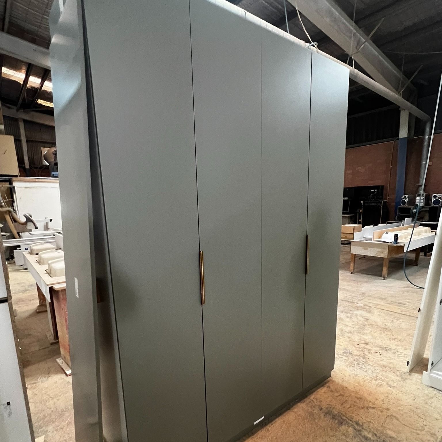 A Large, Grey Wardrobe With Four Doors in a Workshop — Onyx Detailed Joinery in Shellharbour, NSW