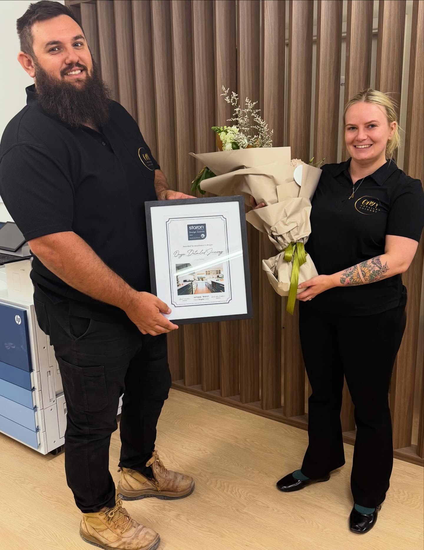 Man Presents Framed Award to Woman Holding Flowers — Onyx Detailed Joinery in Unanderra, NSW