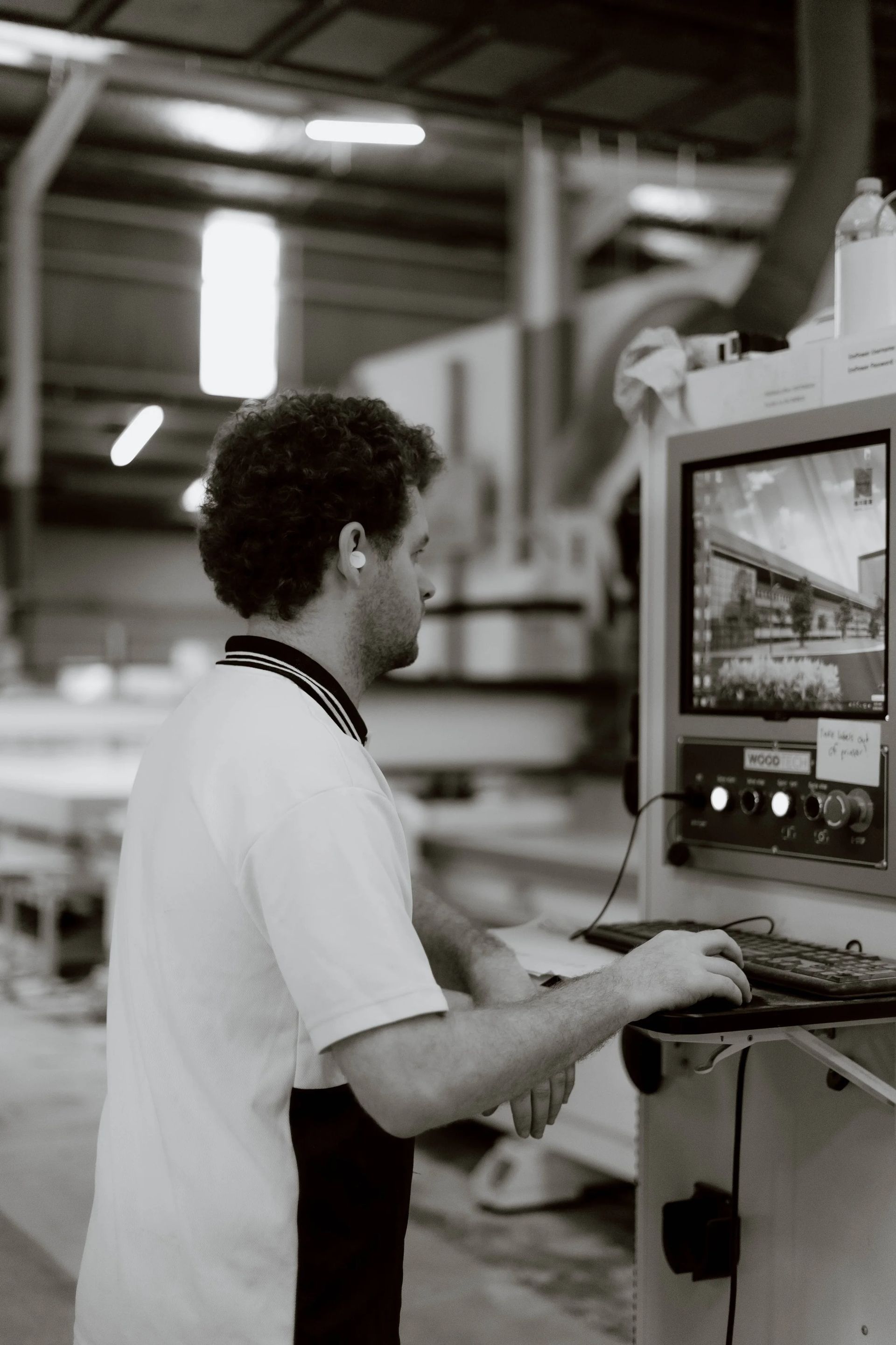 Man in White Shirt Operates Computer in Industrial Setting — Onyx Detailed Joinery in Unanderra, NSW